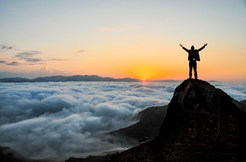 Abundance mindset: a man standing on top of a mountain by the ocean